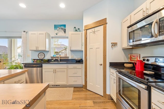 182 Snowy Owl Trl, Bozeman, MT 59718 - kitchen featuring appliances with stainless steel finishes, a sink, light wood-style flooring, recessed lighting, and dark countertops
