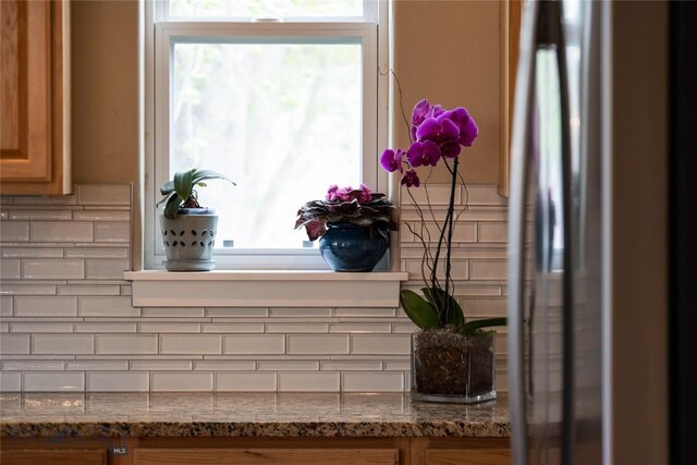 508 Coral Dr, Belgrade, MT 59714 - kitchen view of backsplash, stone counters, brown cabinets, and freestanding refrigerator