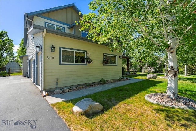 508 Coral Dr, Belgrade, MT 59714 - view of property exterior with a yard, a garage, board and batten siding, and asphalt driveway