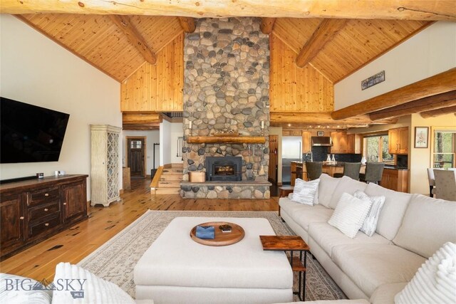 9704 River Rd, Bozeman, MT 59718 - living room featuring light wood-style flooring, wooden ceiling, high vaulted ceiling, beam ceiling, and a fireplace