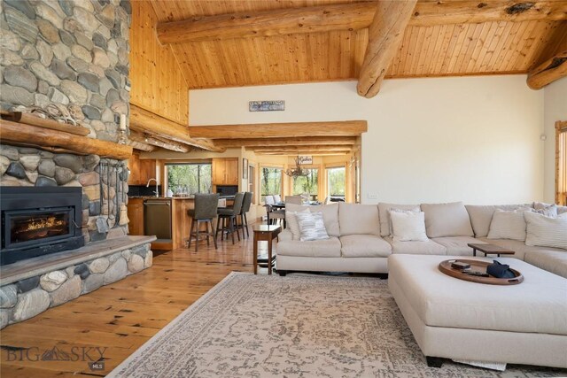 9704 River Rd, Bozeman, MT 59718 - living room featuring light wood finished floors, beam ceiling, wooden ceiling, a stone fireplace, and high vaulted ceiling