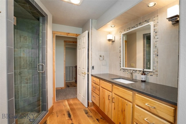 9704 River Rd, Bozeman, MT 59718 - bathroom with wood finished floors, a stall shower, vanity, and tasteful backsplash
