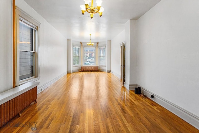 822 W Park St, Butte, MT 59701 - empty room with a chandelier, light wood-style floors, radiator heating unit, and baseboards