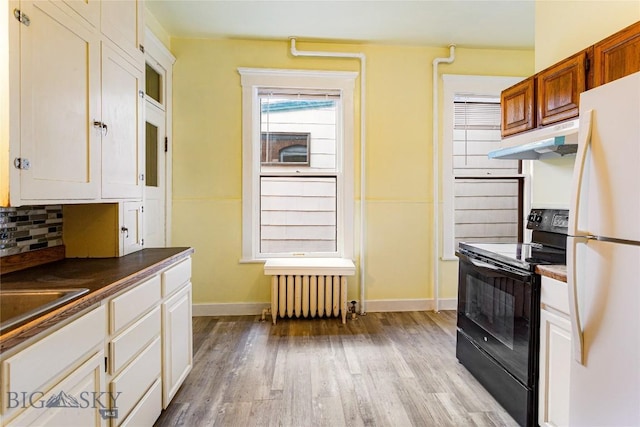 822 W Park St, Butte, MT 59701 - kitchen featuring black / electric stove, freestanding refrigerator, radiator, under cabinet range hood, and light wood finished floors
