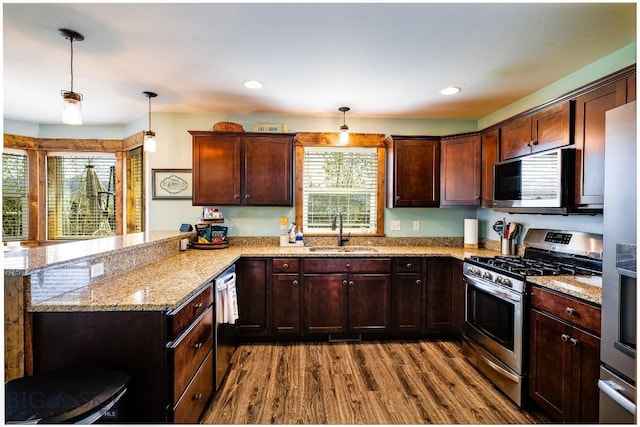 1602 Ingomar Blvd, Belgrade, MT 59714 - kitchen featuring stainless steel appliances, a sink, a peninsula, dark wood finished floors, and pendant lighting
