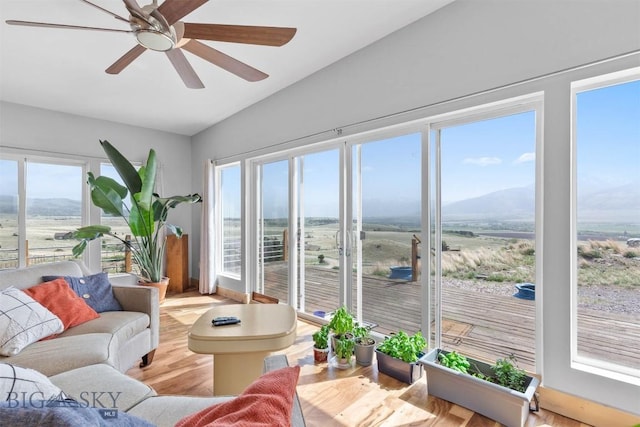 sunroom / solarium featuring lofted ceiling, wood finished floors, and a mountain view