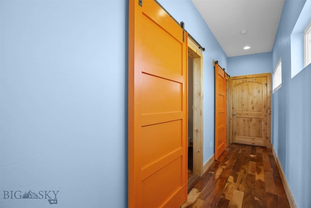 hall featuring a barn door, dark wood-type flooring, baseboards, and recessed lighting
