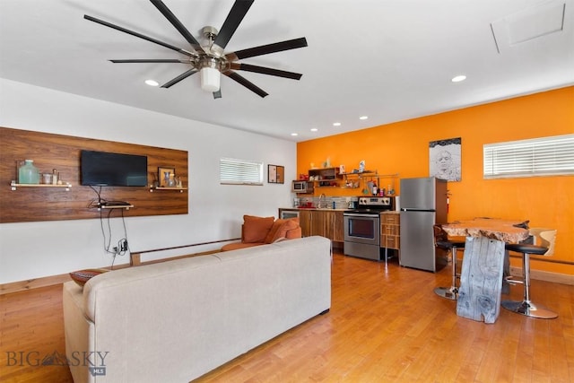 living area with recessed lighting, ceiling fan, light wood-style flooring, and baseboards