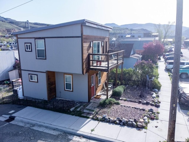 view of front facade with a balcony, a mountain view, and fence