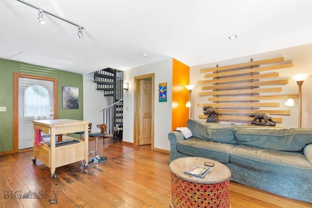 living room featuring stairway, hardwood / wood-style floors, baseboards, and rail lighting