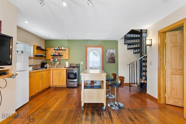 kitchen featuring gas stove, freestanding refrigerator, dark wood-style flooring, open shelves, and recessed lighting