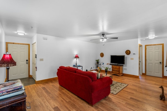 living area with baseboards, light wood finished floors, and a ceiling fan