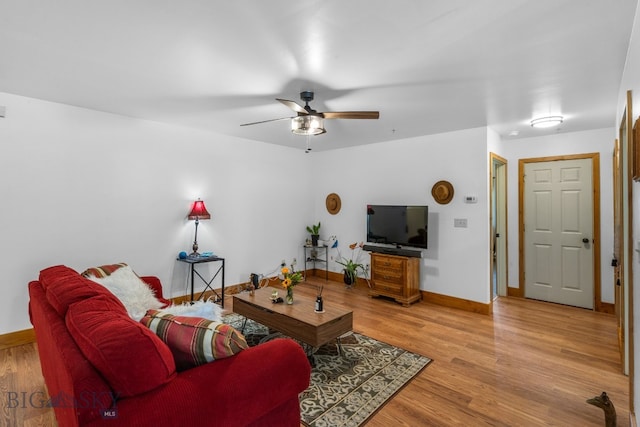 living room featuring light wood-style flooring, baseboards, and a ceiling fan