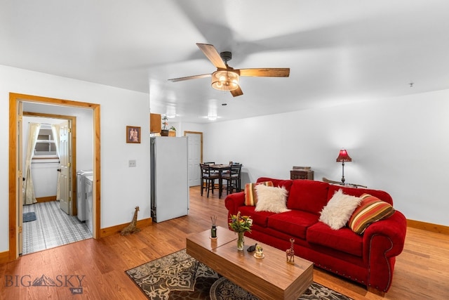 living area featuring baseboards, a ceiling fan, and wood finished floors