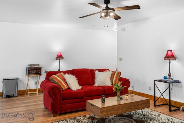 living room featuring ceiling fan, baseboards, and wood finished floors