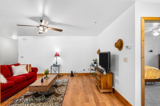 living area with a ceiling fan, wood finished floors, and baseboards