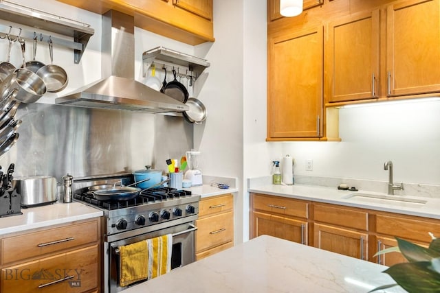 kitchen featuring high end range, island range hood, a sink, light stone counters, and brown cabinetry
