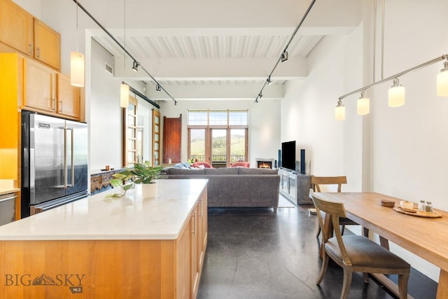 kitchen with high quality fridge, finished concrete flooring, a center island, beamed ceiling, and light countertops