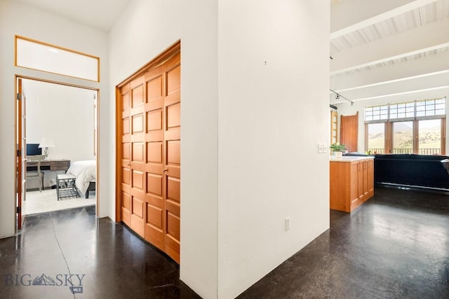 entrance foyer with finished concrete flooring, beam ceiling, and a high ceiling