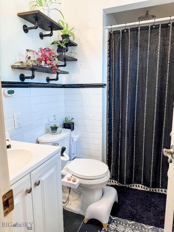 607 Meadowlark Ln, Livingston, MT 59047 - full bathroom with tile walls, toilet, vanity, a shower with shower curtain, and wainscoting