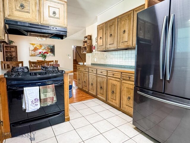 607 Meadowlark Ln, Livingston, MT 59047 - kitchen featuring freestanding refrigerator, black gas range oven, under cabinet range hood, tasteful backsplash, and open shelves