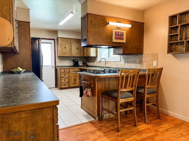 607 Meadowlark Ln, Livingston, MT 59047 - kitchen featuring a peninsula, backsplash, gas cooktop, and freestanding refrigerator