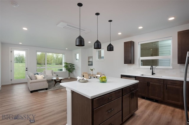 kitchen featuring a sink, light wood-style flooring, light countertops, recessed lighting, and pendant lighting