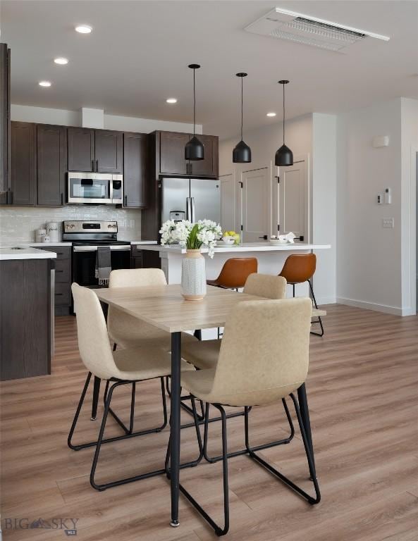 dining space featuring light wood-type flooring, baseboards, and recessed lighting
