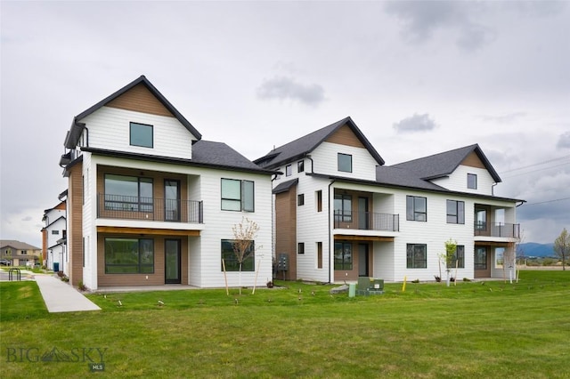 rear view of house with a balcony and a yard