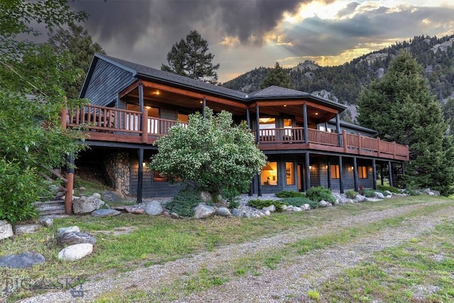 952 N Meadow Creek Rd, Mcallister, MT 59740 - back of house at dusk with a deck with mountain view and stone siding