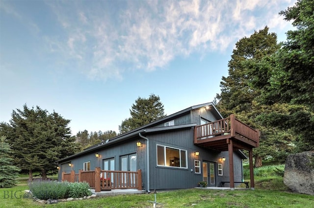 back of house with a lawn, a wooden deck, and french doors