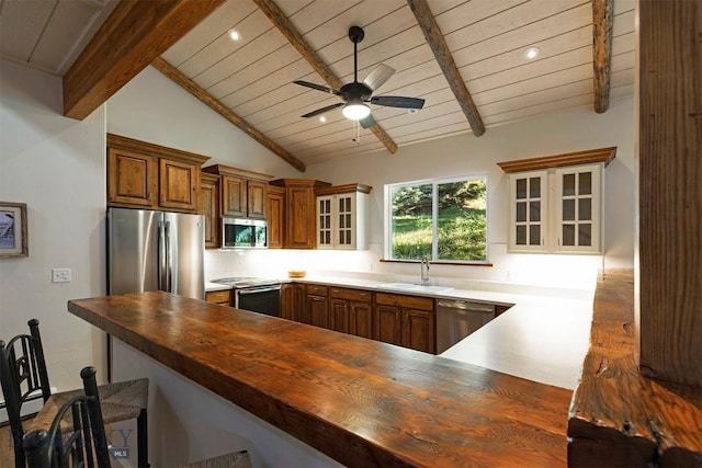 kitchen featuring stainless steel appliances, butcher block counters, a sink, wood ceiling, and glass insert cabinets