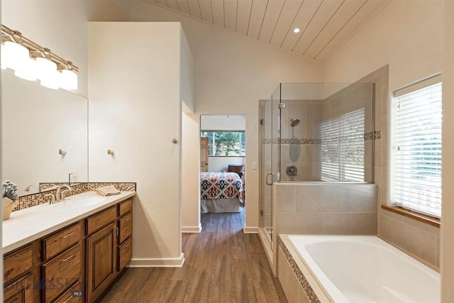 bathroom with connected bathroom, a shower stall, wood finished floors, a bath, and vanity