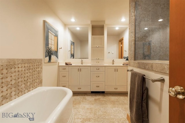 full bath with a freestanding tub, double vanity, recessed lighting, wainscoting, and tile patterned floors