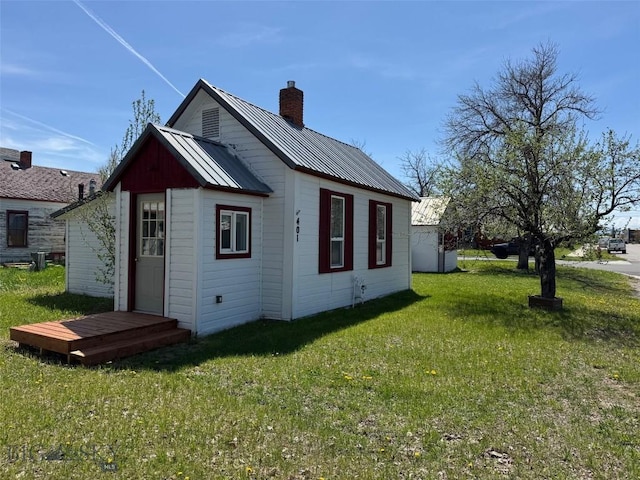 401 E 2nd Ave, Big Timber, MT 59011 - view of side of home featuring a chimney, a lawn, and metal roof