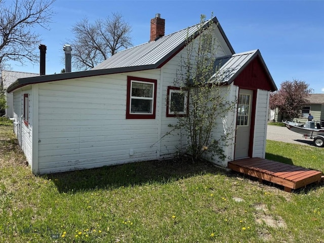 401 E 2nd Ave, Big Timber, MT 59011 - view of side of home with a lawn, a chimney, and metal roof