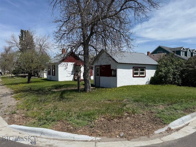 401 E 2nd Ave, Big Timber, MT 59011 - view of side of home with a yard, stucco siding, and an outdoor structure