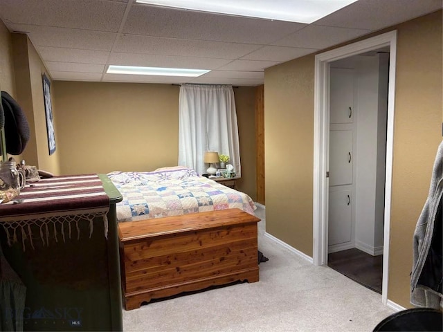 bedroom with a drop ceiling, carpet flooring, and baseboards