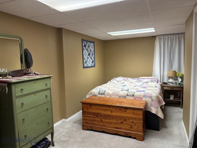 bedroom featuring a paneled ceiling, light colored carpet, and baseboards