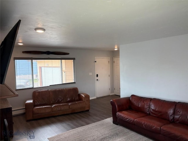 living area featuring wood finished floors, a baseboard heating unit, baseboards, and a ceiling fan