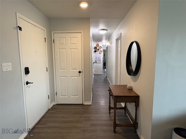 hall featuring dark wood-style flooring and baseboards