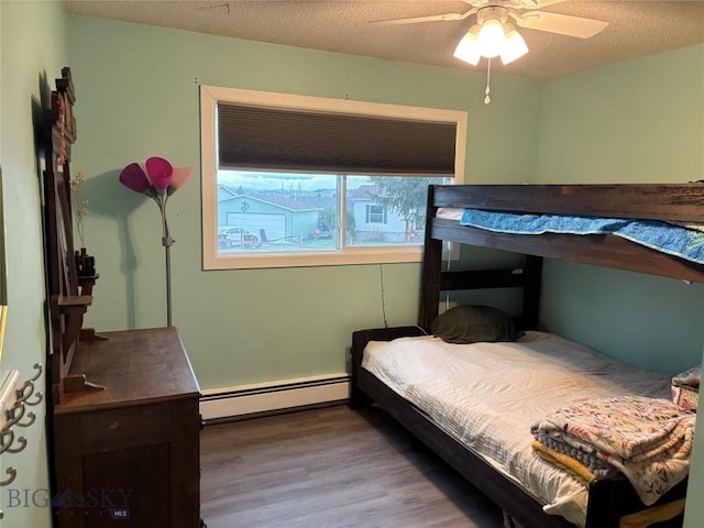 bedroom with a baseboard radiator, wood finished floors, a ceiling fan, and a textured ceiling