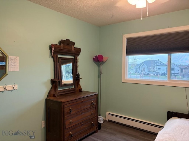 bedroom with baseboard heating, wood finished floors, and a textured ceiling
