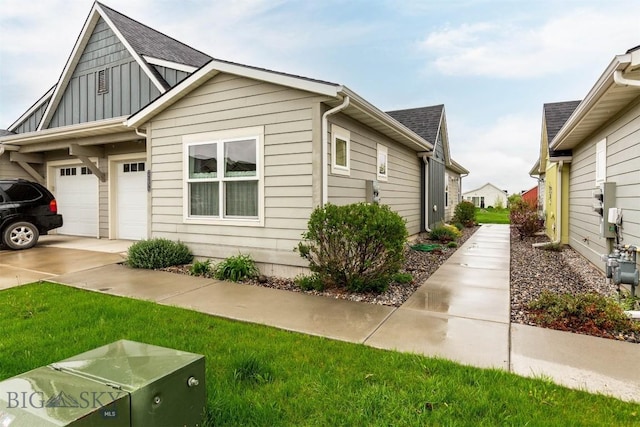 view of front facade featuring board and batten siding, driveway, a shingled roof, and a garage
