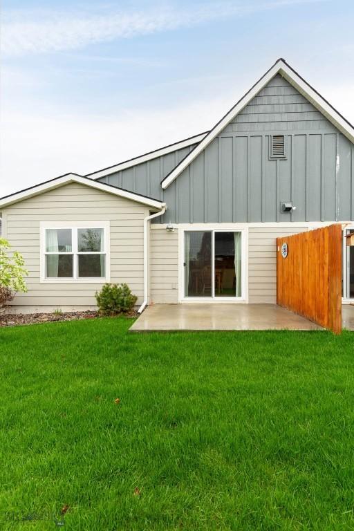 rear view of property with board and batten siding, a patio, and a yard