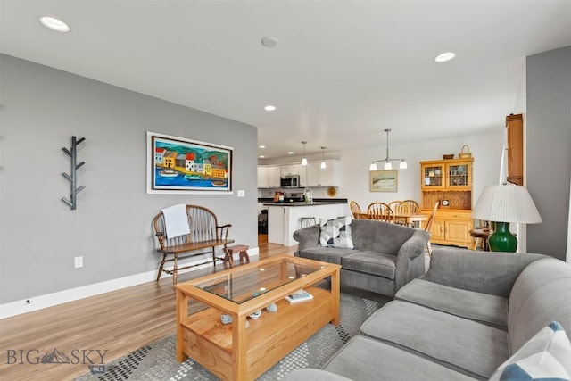 living room with light wood-type flooring, recessed lighting, and baseboards