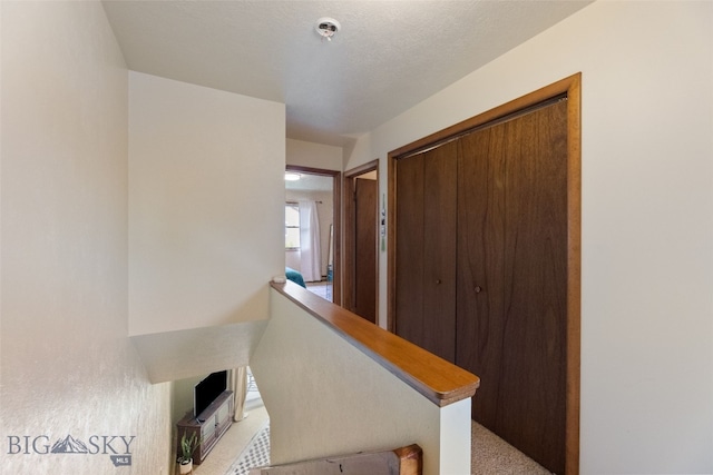 corridor with light carpet and an upstairs landing