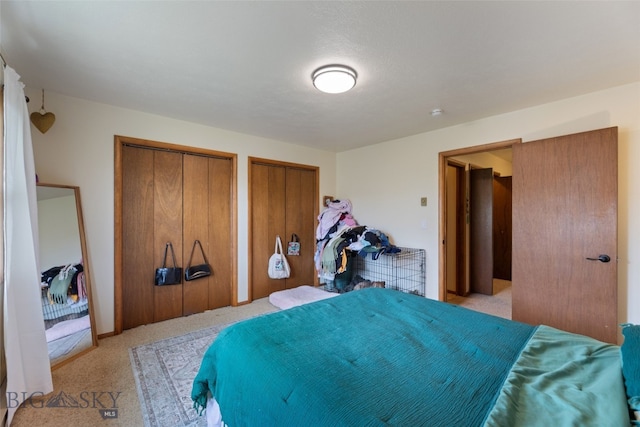 bedroom featuring light carpet and two closets