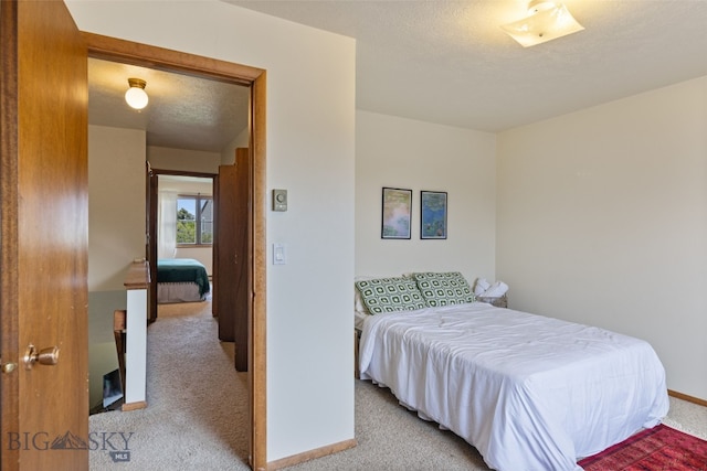 bedroom with carpet flooring, baseboards, and a textured ceiling