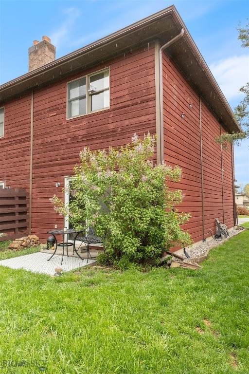 view of side of home featuring a chimney and a lawn